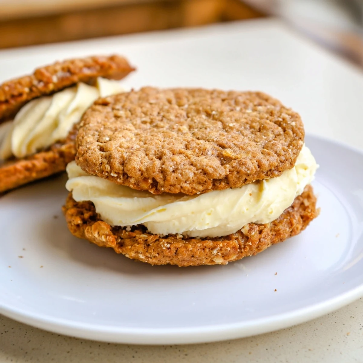 Handheld Gluten Free Oatmeal Creme Pies beside cold milk, chewy cinnamon notes