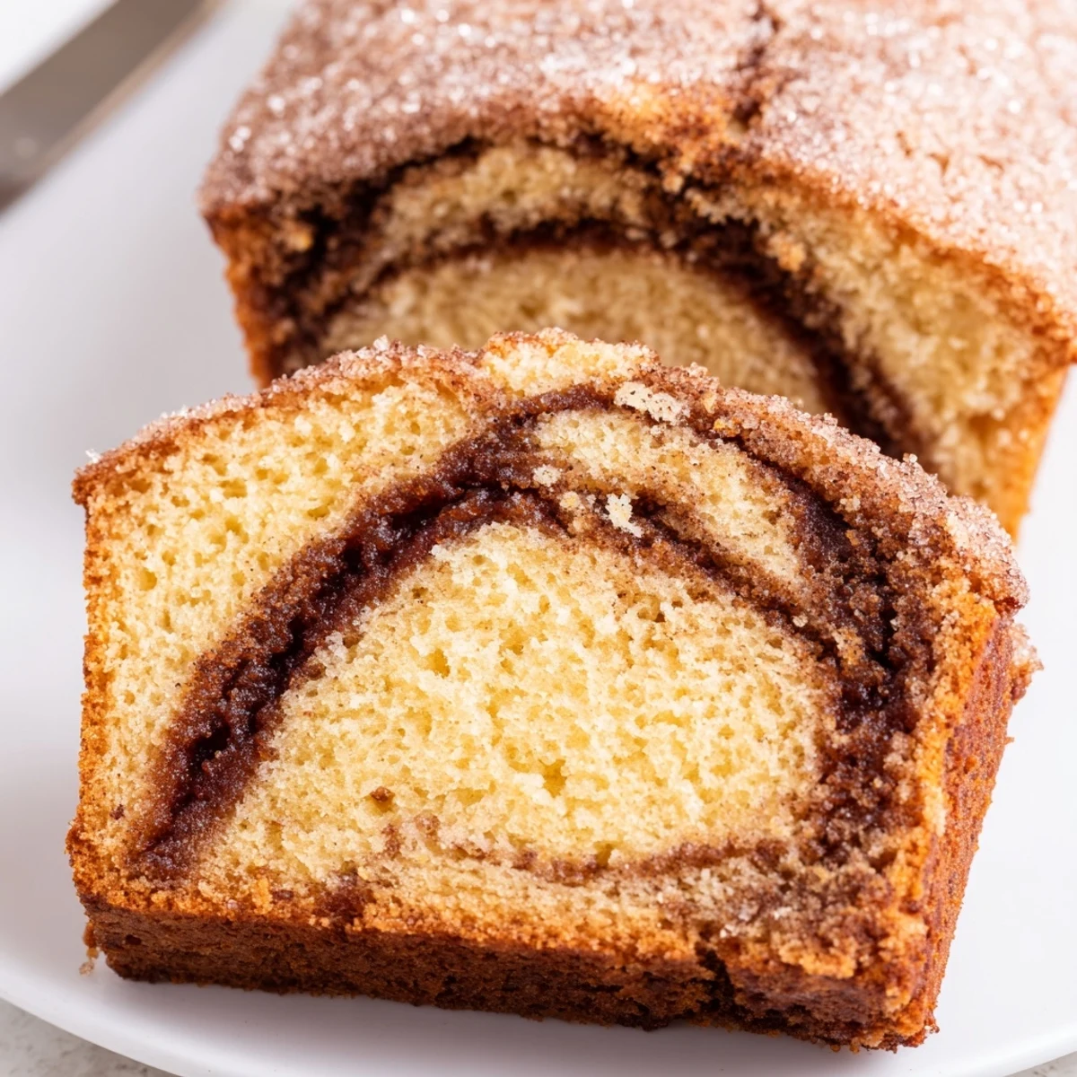 Warm cinnamon donut loaf sliced on a rustic wooden cutting board with crumb topping