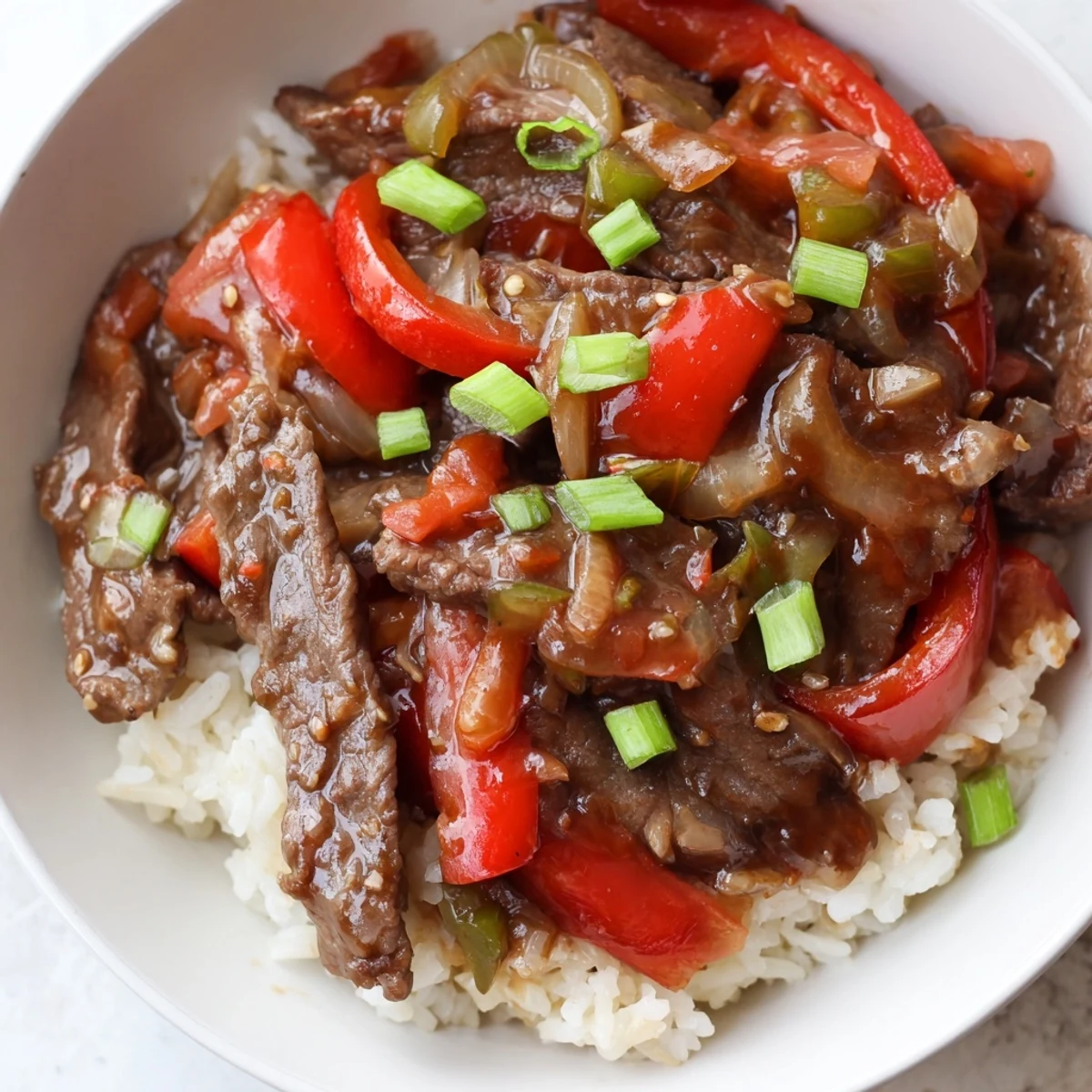 Juicy Slow Cooker Pepper Steak served over fluffy white rice topped with fresh green onions