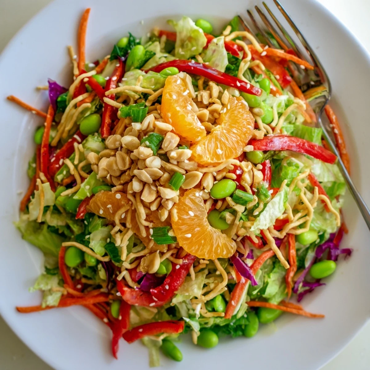 A vibrant Mandarin Sesame Crunch Salad topped with golden noodles and juicy orange segments