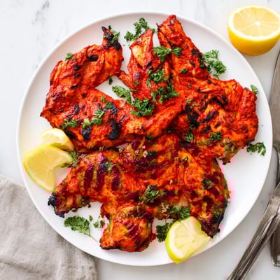 Juicy grilled Peri Peri chicken Portuguese style served with fresh lemon wedges and chopped parsley garnish